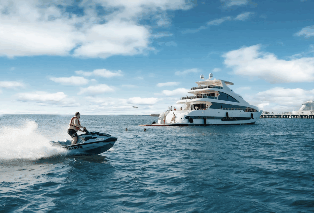 Man on jet ski near luxury yacht with swimmers, in Dubai – United Arab Emirates.
